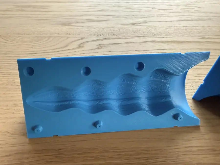The two mould halves lying open, showing the ribbed hollow and the pin holes on the flat face.