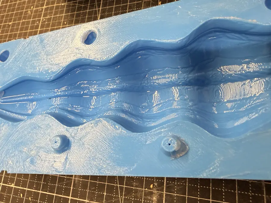 Close-up of a mould half: the flat face round the hollow shines with a thin layer of petroleum jelly.